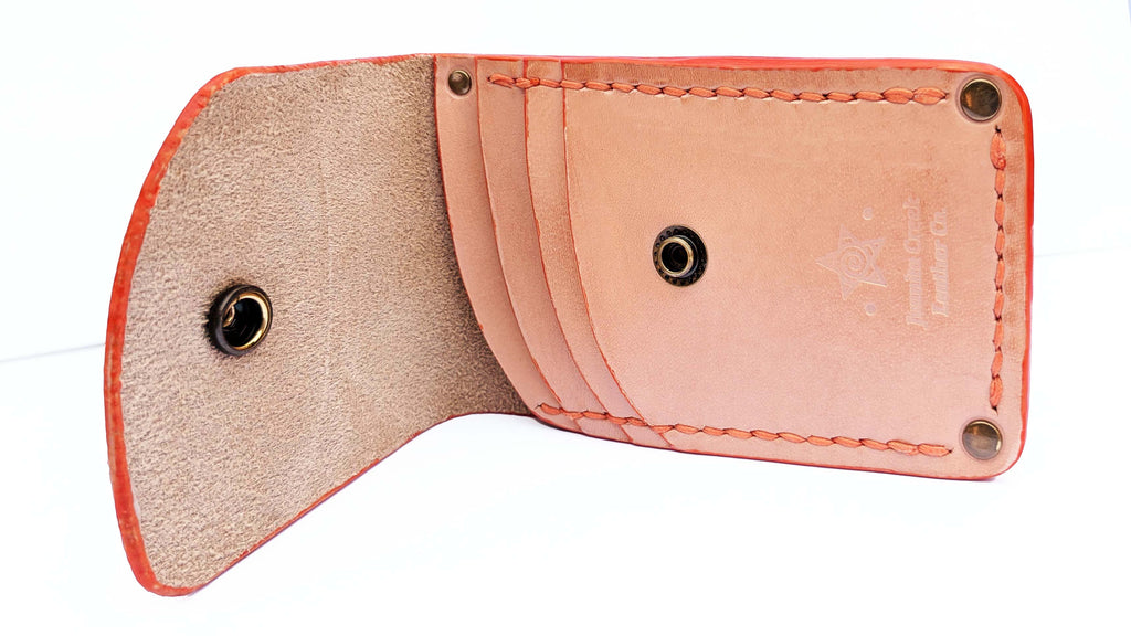 A light peach leather card holder wallet shown open, displaying its interior card slots, tan lining, orange-red stitched edges, and brass snap button closures on a white background.