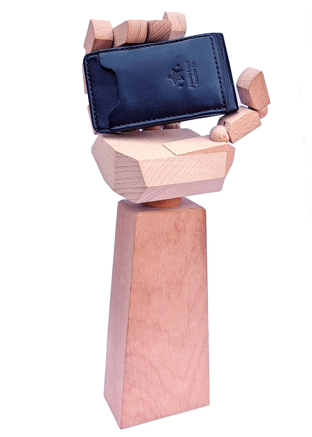 A black leather card holder money clip wallet with an embossed logo, displayed on a stylized wooden hand stand against a white background.