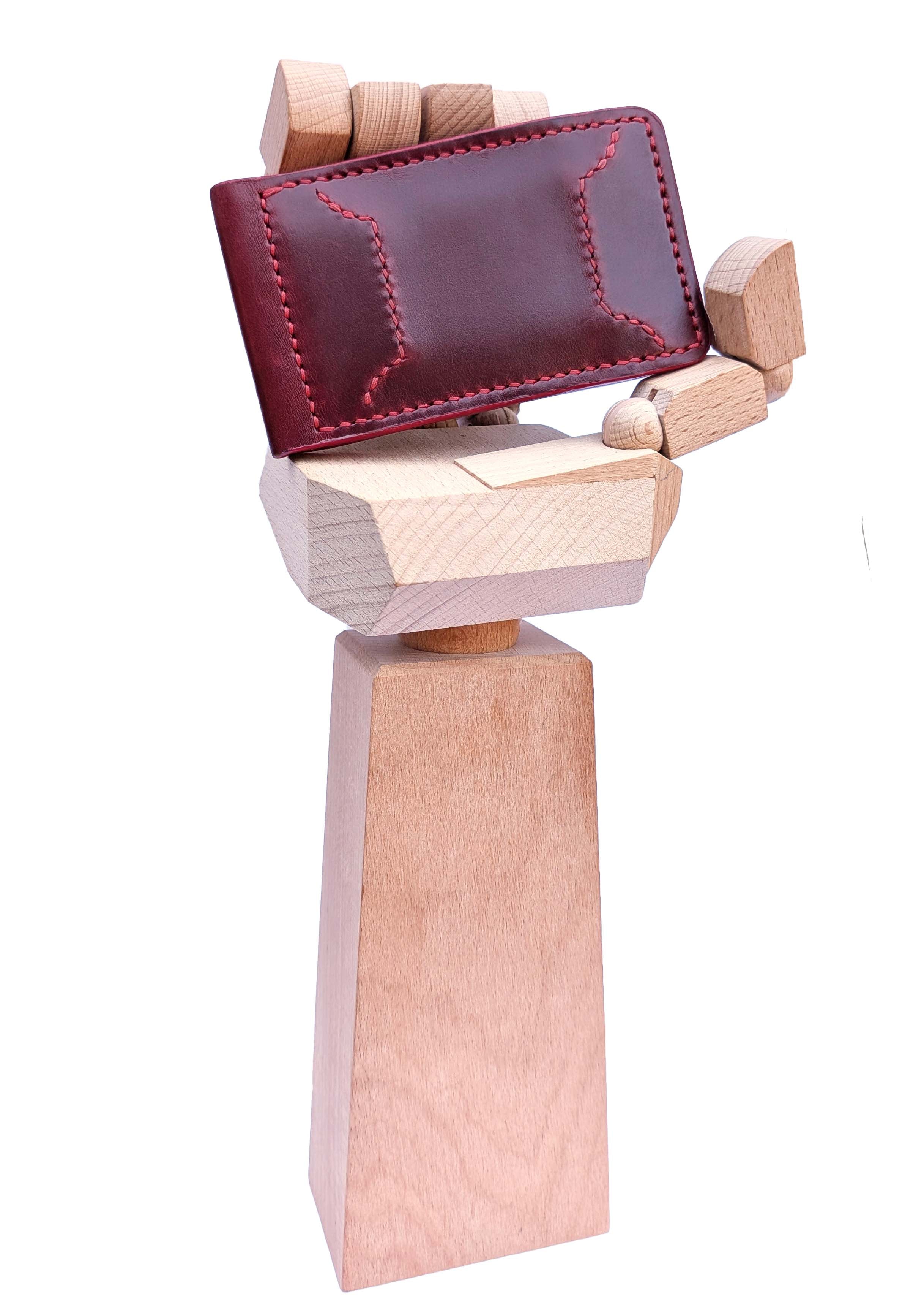 A dark red leather wallet with decorative red stitching, held by a wooden hand-shaped display stand on a white background.